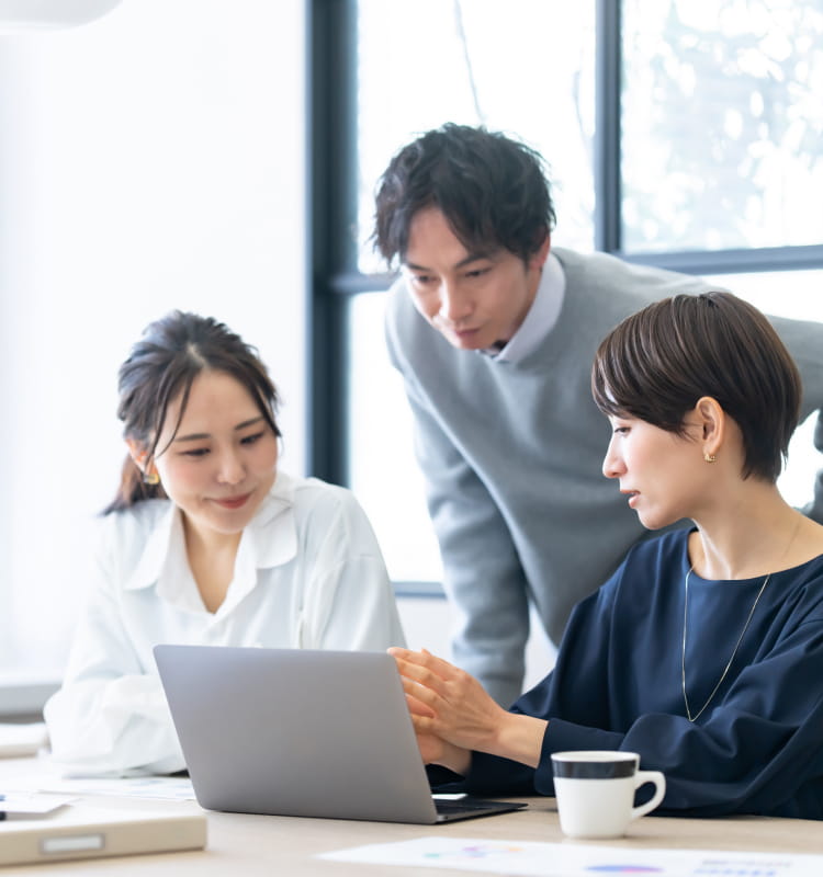 3人の男女がPCを見ながら話している画像